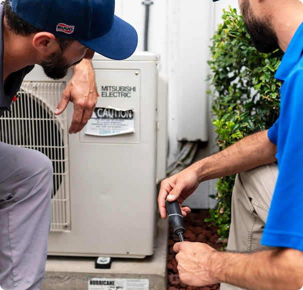HVAC technicians inspecting an outdoor Mitsubishi Electric air conditioning unit