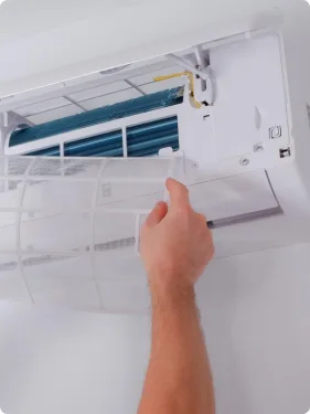 Hand inspecting the filter area of a wall-mounted air conditioner