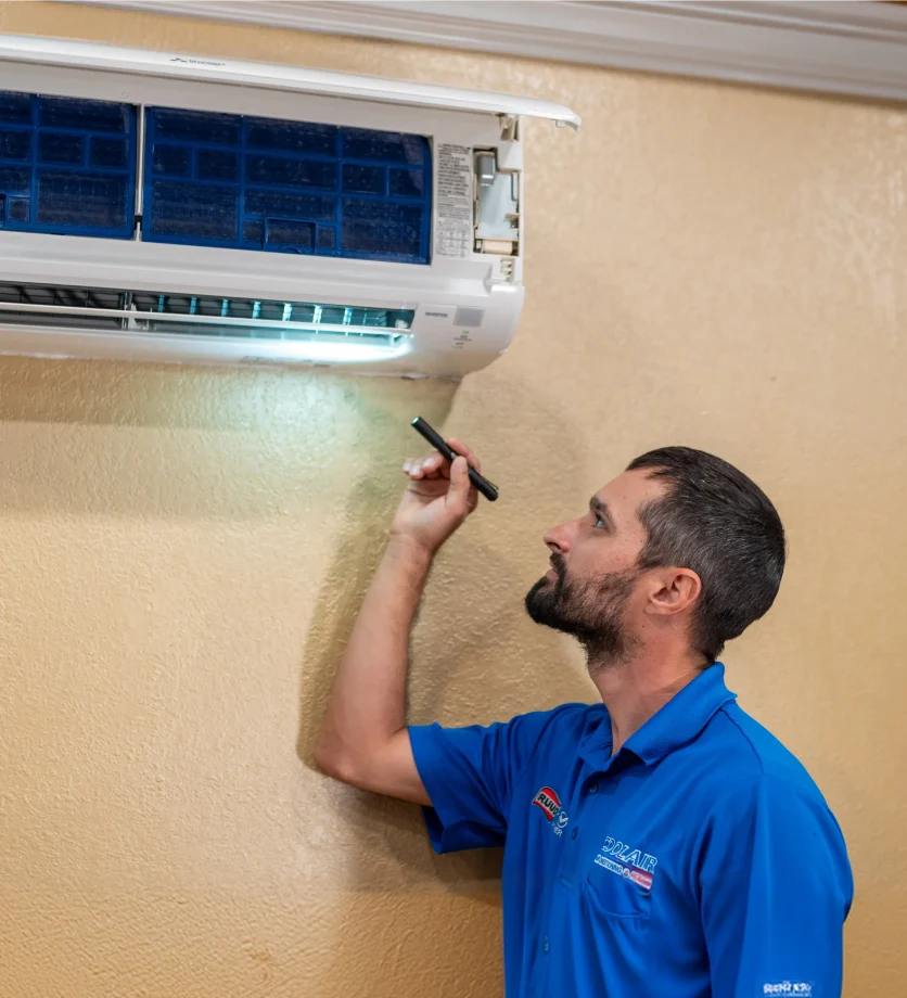 Coolair technician inspecting a wall-mounted air conditioner
