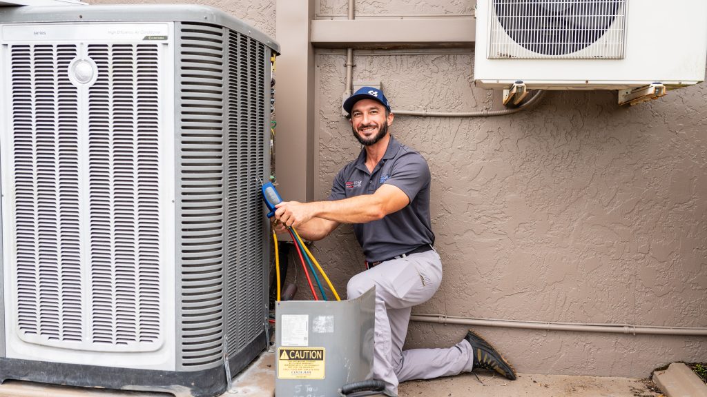 CoolAir technician servicing an outdoor air-conditioning unit