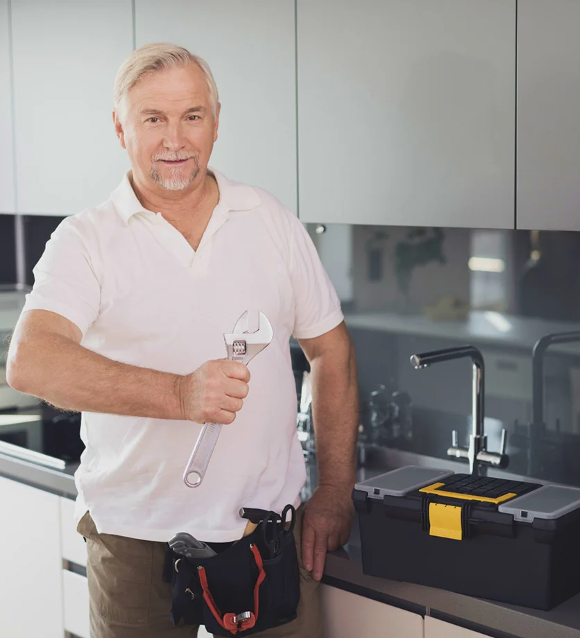 Professional plumber holding a wrench in a residential kitchen