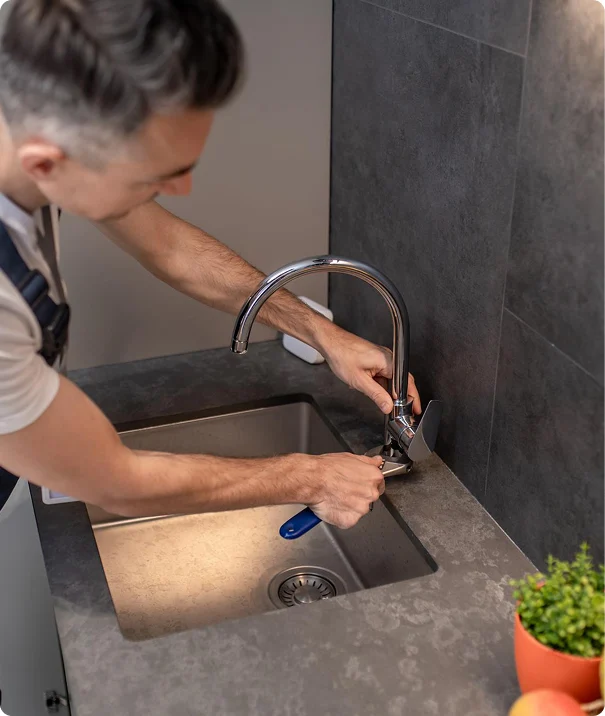 Plumber repairing a kitchen sink faucet