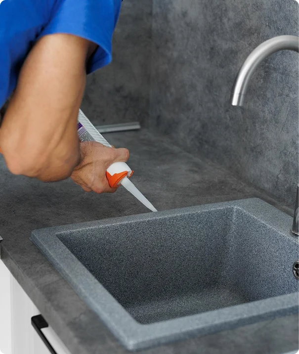 Plumber sealing the edges of a newly installed kitchen sink
