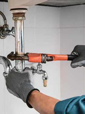 Plumber repairing a pipe connection under a sink
