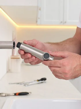 Plumber inspecting a kitchen faucet component