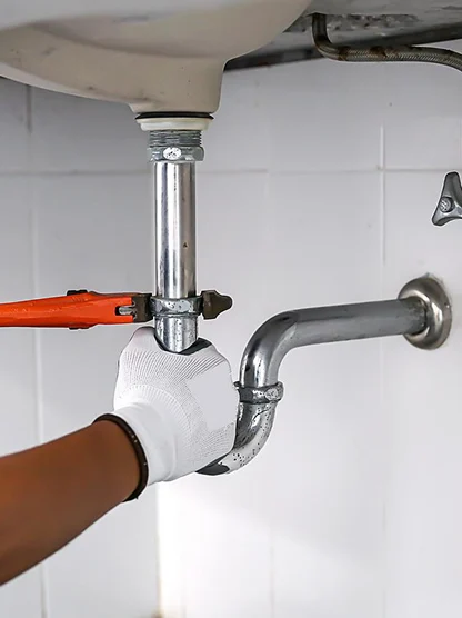 Plumber repairing a drain pipe under a bathroom sink