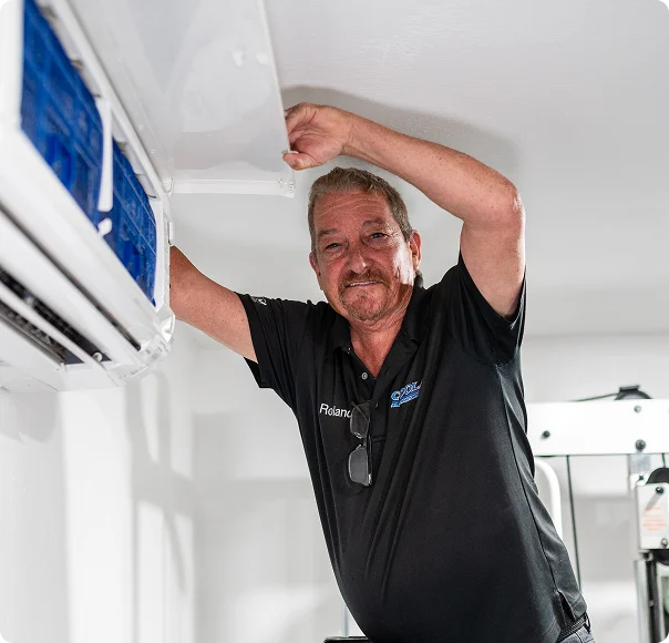 HVAC contractor inspecting and maintaining a wall-mounted air conditioning system.