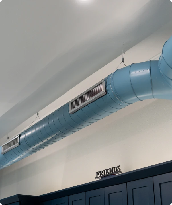 Exposed blue ventilation duct with an air grille.