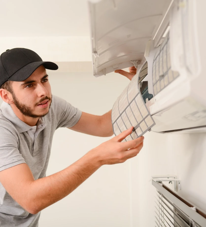 Technician removing a filter from a wall-mounted air conditioner.