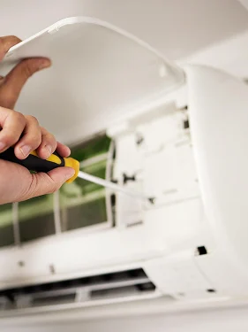 HVAC technician repairing the internal components of a wall-mounted air conditioning unit.