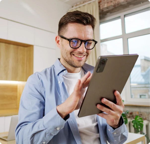 Man wearing glasses using a tablet at home